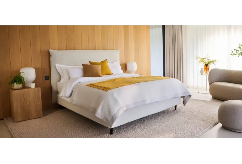 Air storage bed on slim legs in a calm bedroom, shown in boucle with an optional headboard