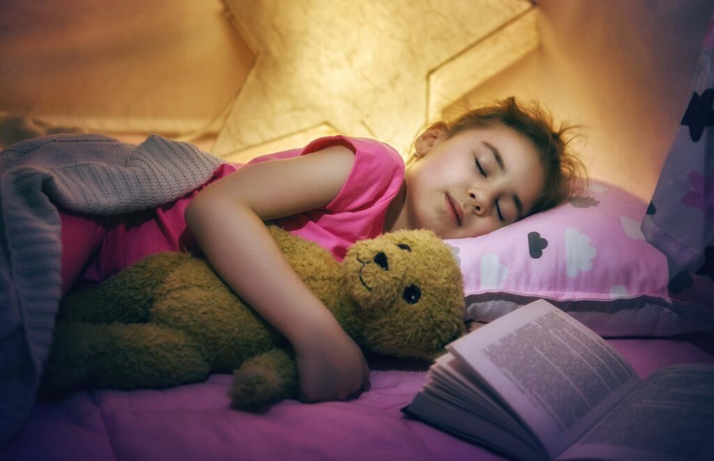 Little girl sleeping with a book beside her