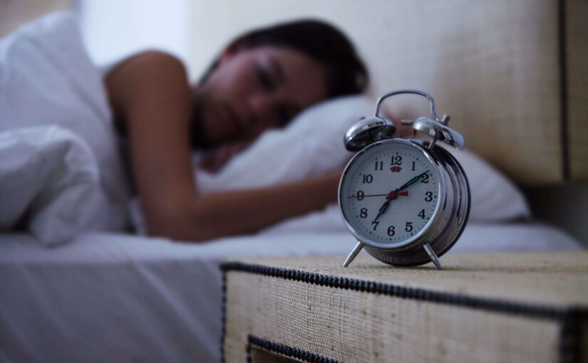 Woman asleep with clock on a nightstand