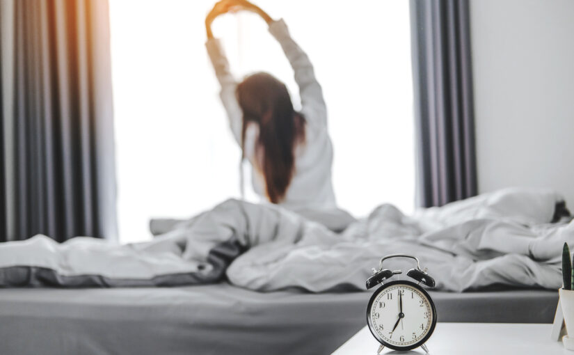 Woman wakes up and stretches on bed
